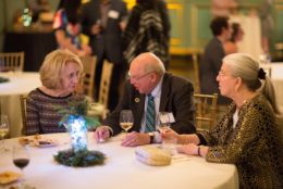 two women and a man seated at a table during event