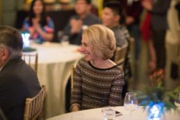 woman seated at table smiling as she looks on