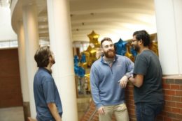 three men speaking in flaum atrium