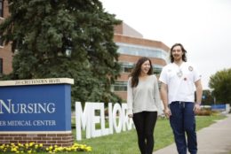 two people walking outside of SON with meliora letters behind them