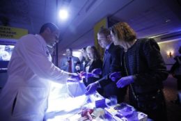 man in white coat giving demonstration two a group of people