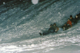 group of students sledding down snowy hill