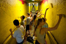 group of students painting tunnel walls yellow