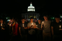 group of students at night with candle vigil with rush rhees tower lighted up in background