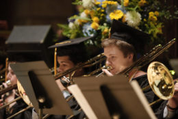 graduates performing on stage - two playing the trombone