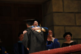 two people in cap and gown giving a hug