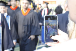 parent taking photo with iphone of passing graduates