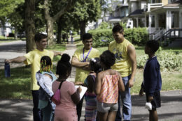 three students talking to a group of younger kids outdoors