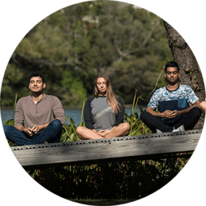 three people meditating outdoors