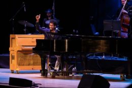 man giving thumbs up at piano on stage during performance