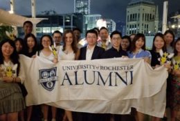 group holding a rochester alumni banner at an event