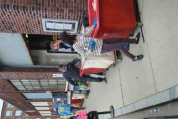 several people on sidewalk preparing bins