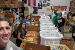 group of people posing for photo while preparing care packages in laundry baskets