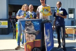 four people posing for photo in front of garbage bin with harry potter on it