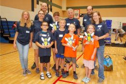 group of adults and four kids in a gym posing for photo