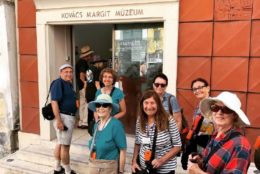 group of people smiling outside of orange entry way of a museum