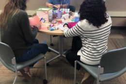 three people sitting at table preparing crafts