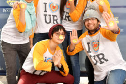 five women and one man wearing colorful i heart UR tshirts posing for photo booth