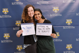 two women holding thank you card in front of UR backdrop