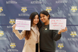 two women holding thank you card in front of UR backdrop