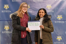 two women holding thank you card in front of UR backdrop