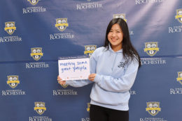 woman holding thank you card in front of UR backdrop