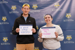 man and woman holding thank you card in front of UR backdrop