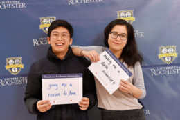 man and woman holding thank you card in front of UR backdrop