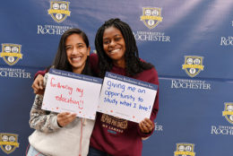 two women holding thank you card in front of UR backdrop