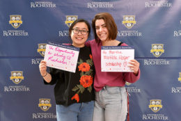 two women holding thank you card in front of UR backdrop