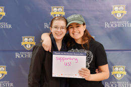 two women holding thank you card in front of UR backdrop