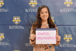 woman holding thank you card in front of UR backdrop