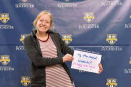 woman holding thank you card in front of UR backdrop