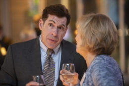 man and woman speaking both holding a wine glass
