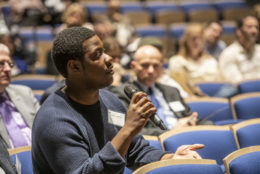 man seated in audience with microphone asking a question