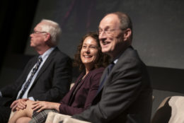 two man and a woman on stage during an event smiling