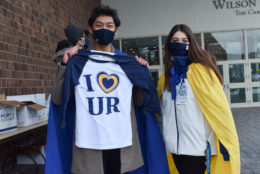 two people holding up their i heart UR tshirts and posing for photo wearing masks