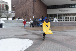 woman facing camera wearing a yellow cape long dark hair and a dark blue mask