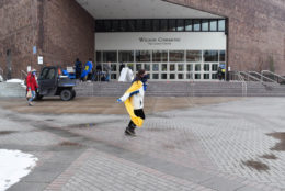 woman facing camera wearing a yellow cape long dark hair and a dark blue mask