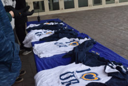 table outside building with several piles of i heart UR tshirts