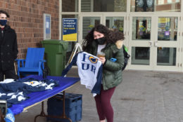 woman picking up hear i heart ur t-shirt from table outside of a building