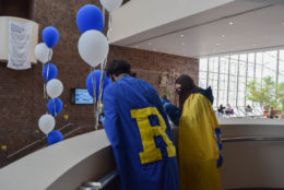 two people wearing large capes with R's on the back looking over balcony