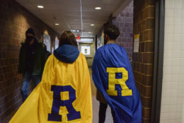 two people with large caps and an R on the back walking down hall