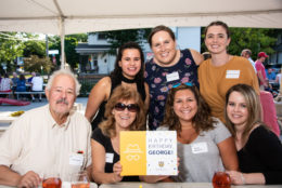 six women and a man posing for photo during an event