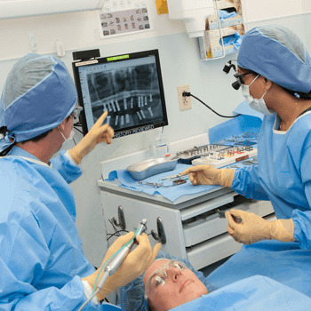 two doctors performing oral surgery on a patient.