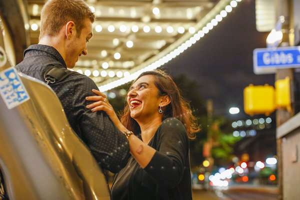 A man and woman speaking to each other under a light marquee