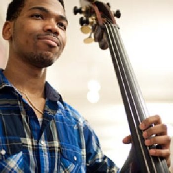 a student poses as he holds a guitar in his hand.