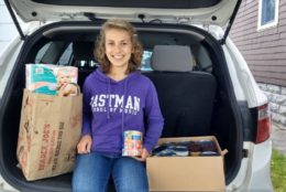 woman smiling wearing purple eastman hoodie in trunk of car with supplies to donate
