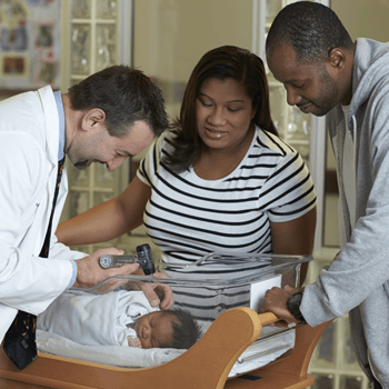 a doctor examines a newborn child as the parents watch.