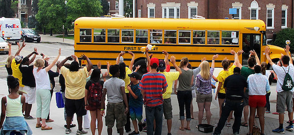 Group of people facing towards a yellow school bus